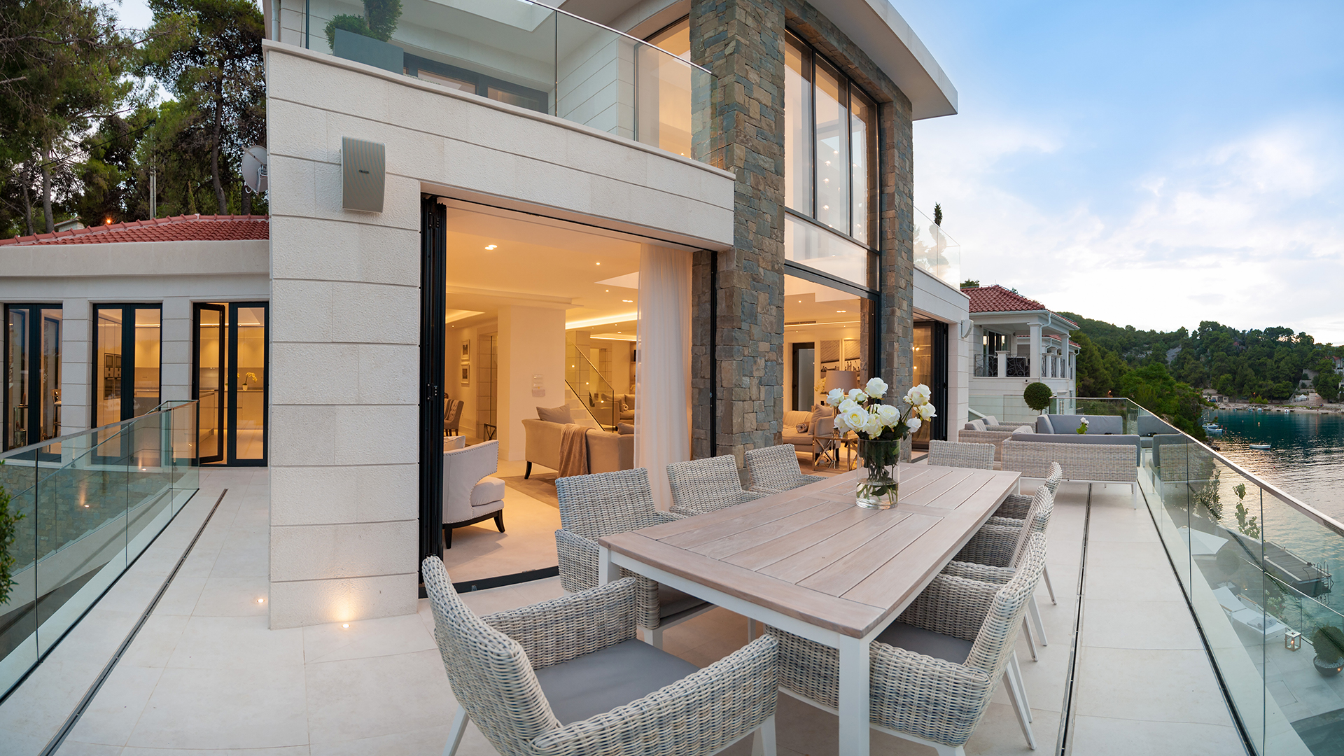The large alfresco dining area in front of the stone luxury home.