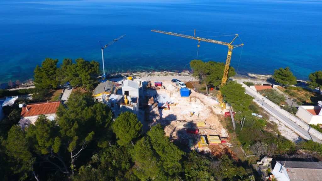 The drone photography of a yellow crane above the construction site.